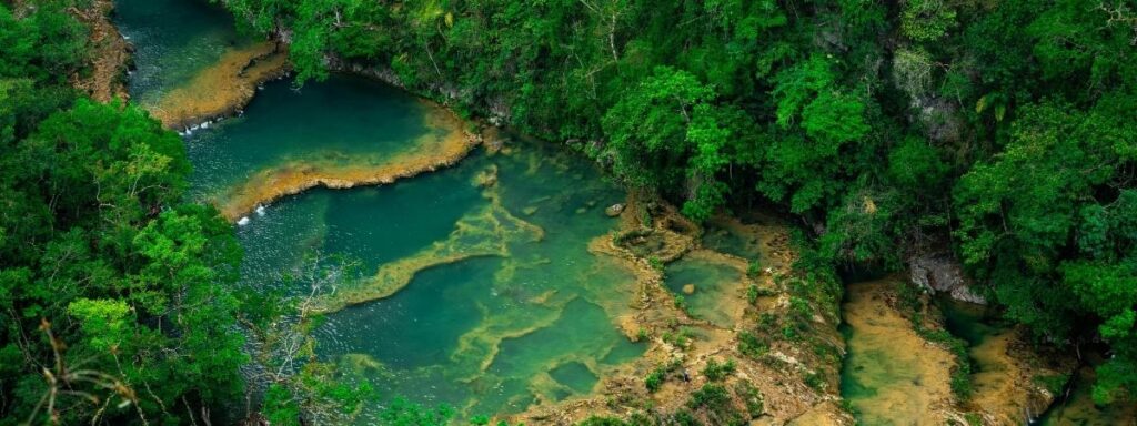 Aerial view of the turquoise limestone pools of Semuc Champey surrounded by dense tropical jungle, illustrating the humid climate where the Best Guatemalan Coffee Beans from Cobán are grown.